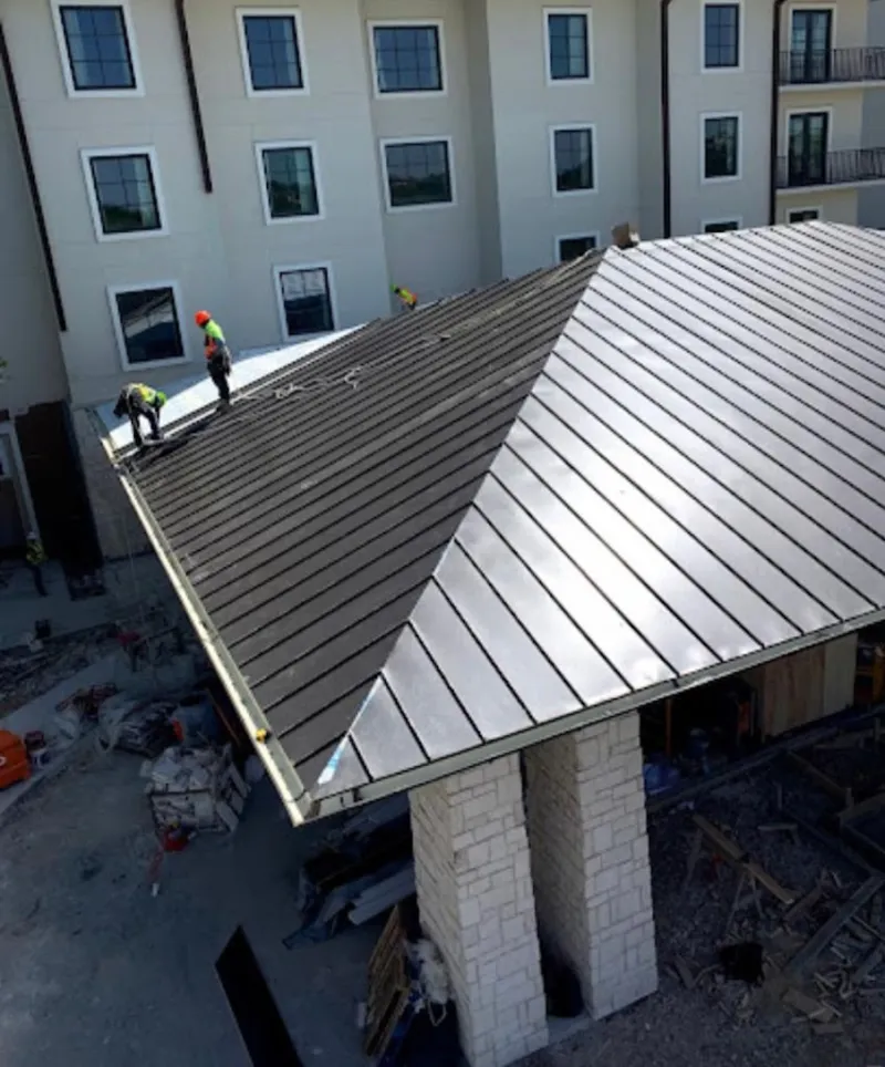 Crew installing standing seam metal roof panels on a commercial project in Fostoria